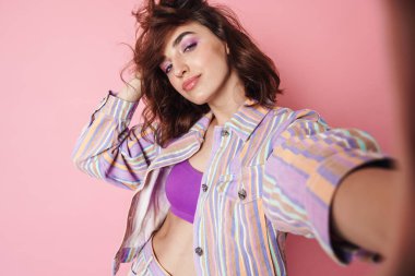 Kızıl saçlı çekici bir kadının pembe arka planda izole edilmiş selfie çekerken görüntüsü.