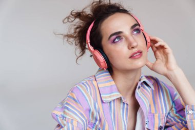 Beyaz arka planda izole edilmiş kablosuz kulaklık kullanan kızıl saçlı kadın görüntüsü