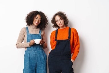 Tulum giymiş, kameraya bakıp beyaz arka planda izole edilmiş iki kadının portresi.