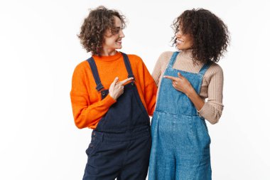 Tulum giymiş iki mutlu kadının portresi. Birbirlerine sarılıp işaret ediyorlar. Beyaz arka planda izole bir şekilde.