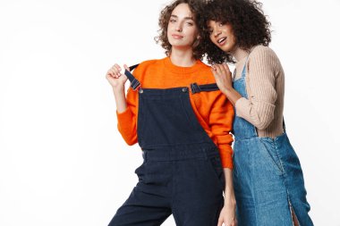 Tulum giymiş, kameraya bakıp beyaz arka planda izole edilmiş iki kadının portresi.