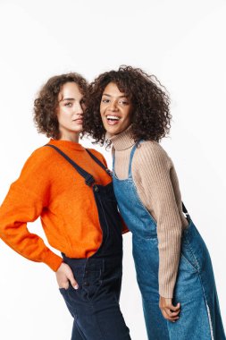 Tulum giymiş gülümseyen, kameraya bakıp beyaz arka planda izole edilmiş bir şekilde sarılan çok uluslu kadınların portresi.