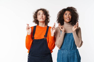 Tulum giymiş çok uluslu güzel kadınların portresi beyaz arka planda izole bir şekilde parmaklarını çapraz yaparak yukarı bakıyor.