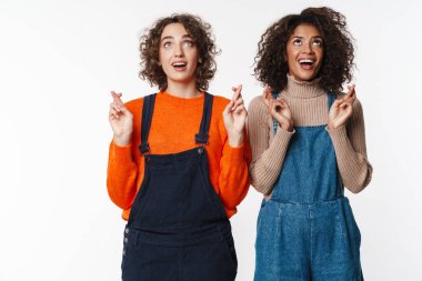 Heyecanlı çok uluslu kadın portresi yukarı bakan beyaz arka planda parmakları çapraz