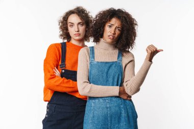 Tulum giymiş, kameraya bakıp beyaz arka planda izole bir şekilde başparmağını gösteren çok uluslu kadınların portresi.