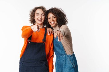 Tulum giymiş gülümseyen çok uluslu kadınların portresi beyaz arka planda izole edilmiş kamerayı gösteriyor ve işaret ediyor.