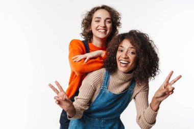 Tulumlu, neşeli, çok uluslu kadınların portresi beyaz arka planda izole edilmiş barış işareti yapıyor.