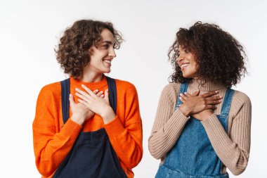 Tulum giymiş, gülümseyen ve beyaz arka planda izole edilmiş göğüslerin üzerinde el ele tutuşan çok uluslu güzel kadınların portresi.