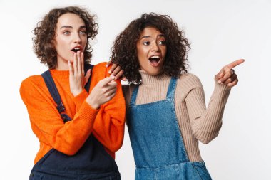 Heyecanlı çok uluslu kadın portresi beyaz arka planda izole edilmiş parmakları işaret ediyor.