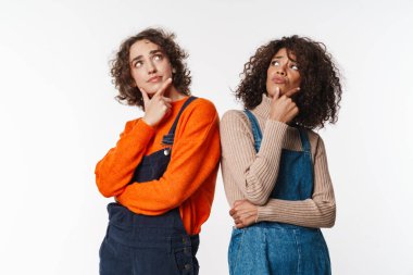 Kafası karışmış çok uluslu kadın portresi, beyaz arka planda tek başına düşünüp yukarı bakıyor.