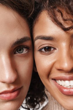 Beyaz duvar arkasında izole edilmiş mutlu, gülümseyen, çok ırklı kız arkadaşlarının yakın plan fotoğrafı..