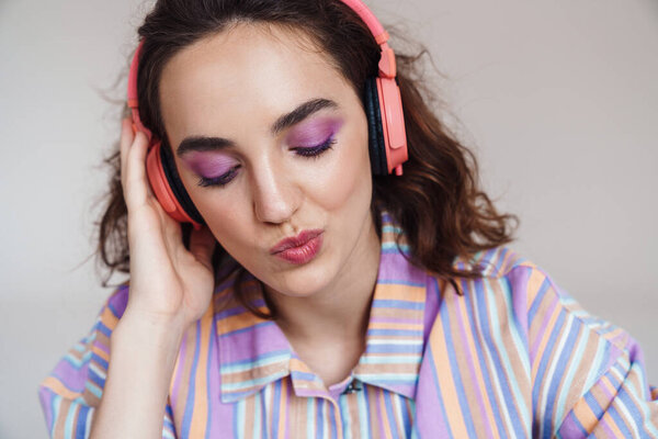 Изображение рыжей мыслящей женщины, использующей беспроводные наушники на белом фоне