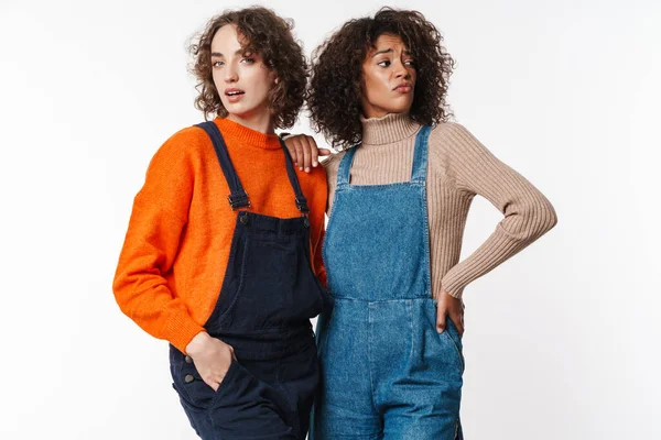 Kafası karışmış çok uluslu kadın portresi beyaz arka planda yalnız poz veriyor ve sarılıyor.