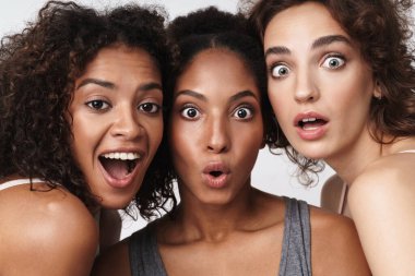 Üç tane çok ırklı kadının portresi bir arada durup beyaz arka planda izole edilmiş kameraya bakıyor.