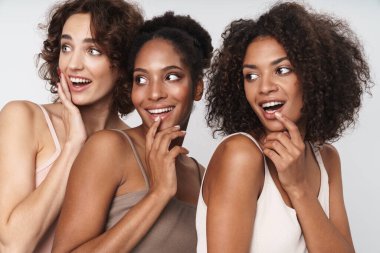 Beyaz arka planda yalnız kalmış, gülümseyen ve yan bakan üç hayret dolu kadının portresi.