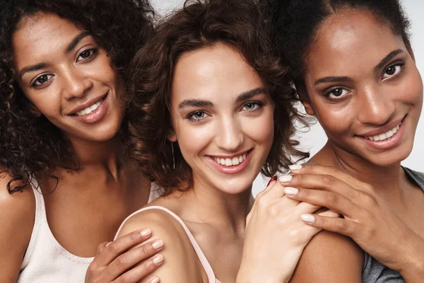 Beyaz arka planda izole edilmiş, birbirine sarılıp gülümseyen üç mutlu kadının portresi.
