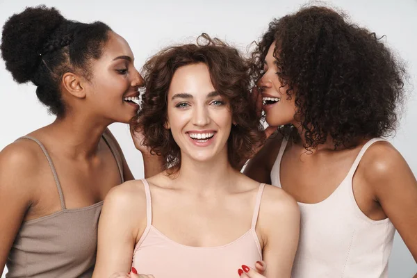 三个快乐的多民族女人站在一起 在被白色背景隔离的女孩的耳朵中谈论秘密的画像 — 图库照片