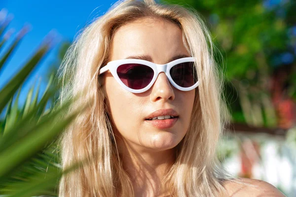 Güneş gözlüklü, yaz plajına bakan baştan çıkarıcı sarışın kadın.