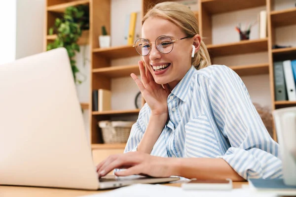 Obraz Szczęśliwej Kobiety Korzystającej Słuchawek Śmiejącej Się Podczas Pracy Laptopem — Zdjęcie stockowe