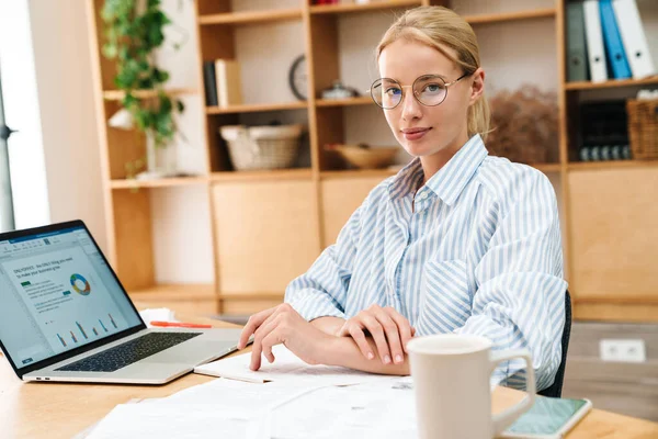 Imagem Mulher Loira Séria Óculos Trabalhando Com Papéis Laptop Mesa — Fotografia de Stock