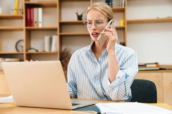 Imagem Empresária Atraente Descontente Falando Celular Enquanto Trabalhava Com Laptop — Fotografia de Stock