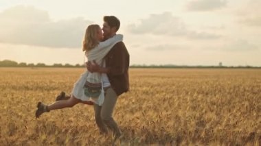 Yakışıklı bir genç adam tarlada güzel bir kadını döndürüyor.