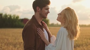 Gülümseyen çift, sahada yürürken sarılıyor.