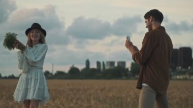 Çekici genç adam sahada güzel kız arkadaşının fotoğrafını çekiyor.