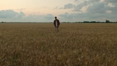 Mutlu bir genç adam yaz zamanı sahada yürüyor.