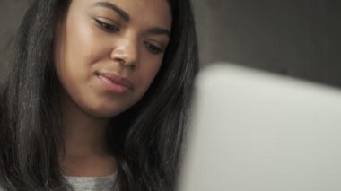 Evde dizüstü bilgisayar kullanan genç bir kadın.