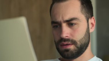 Evinde elinde belgelerle oturan konsantre olmuş genç bir adam.