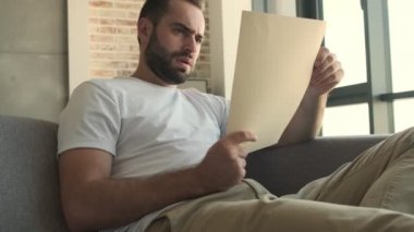 Genç yakışıklı, elinde belgelerle evde oturan ciddi bir adamı strese soktu.