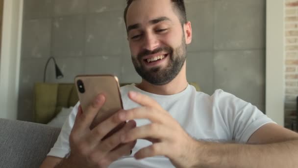 Jeune Homme Heureux Beau Assis Intérieur Maison Tout Utilisant Téléphone — Video