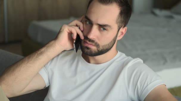 Young Serious Confused Man Sitting Indoors Home Talking Mobile Phone — Stock Video