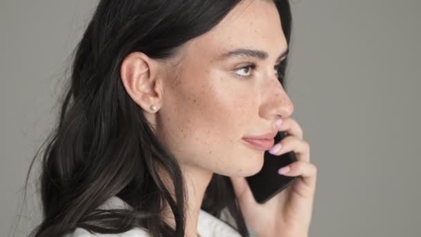 Крупным Планом Улыбающаяся Молодая Женщина Делает Жест Молчания Разговаривая Телефону — стоковое видео