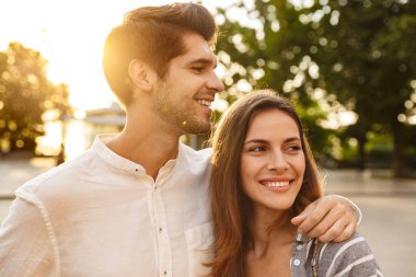 Güneşli bir günde, şehir caddesinde yürüyen mutlu bir çift.