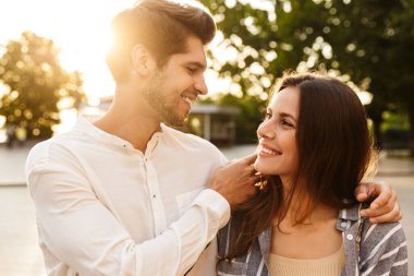 Kafkasyalı genç bir çiftin şehrin sokaklarında retro kamerayla yürürken gülümseyip kucaklaşması.