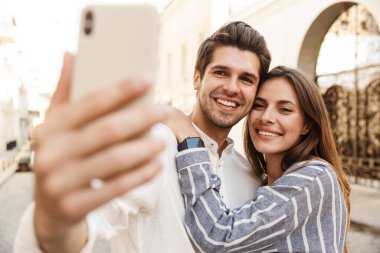 Kafkasyalı mutlu bir çiftin şehir caddesinde yürürken gülümseyip selfie çektiği görüntüler.