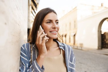 Sokakta akıllı telefon kullanan mutlu bir kadın.