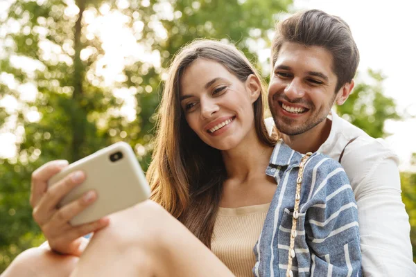 Image Young Caucasian Happy Couple Smiling Hugging While Holding Cellphone — Stock Photo, Image