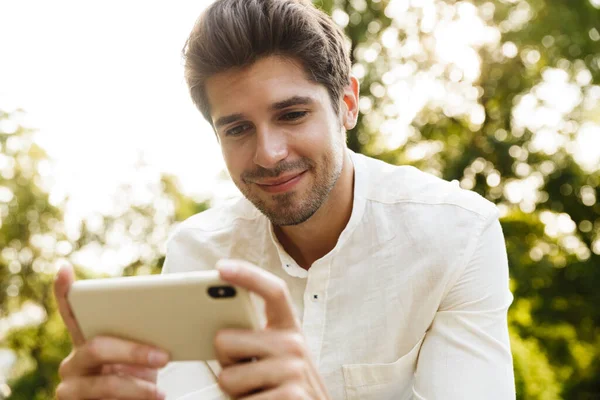 Bild Unga Kaukasiska Brunett Man Ler Och Håller Mobiltelefon När — Stockfoto