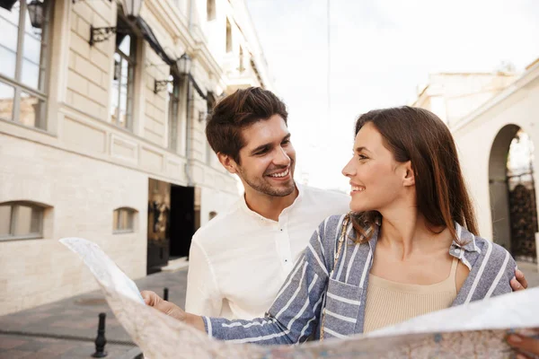 Imagen Hermosa Pareja Caucásica Joven Sonriendo Sosteniendo Mapa Mientras Camina — Foto de Stock