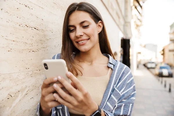 Imagem Jovem Mulher Morena Caucasiana Sorrindo Segurando Celular Enquanto Caminhava — Fotografia de Stock