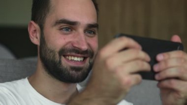 Evde cep telefonu kullanan mutlu, genç bir adam.