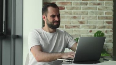 Evde dizüstü bilgisayar kullanan hoşnutsuz bir genç.