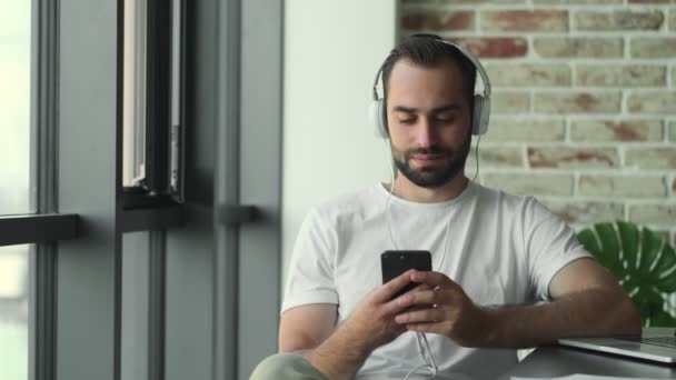 Jonge Tevreden Man Die Thuis Muziek Luistert Met Hoofdtelefoon Terwijl — Stockvideo