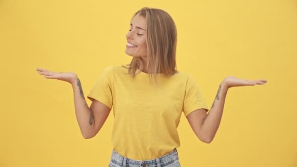 Una Joven Rubia Sonriente Con Camiseta Amarilla Sostiene Espacio Libre — Vídeo de stock