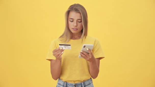 Egy Elégedett Fiatal Használja Hitelkártyáját Miközben Pénzt Utalnak Sárga Háttér — Stock videók
