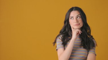 Rüya gören genç bir kadın sarı arka planda izole edilmiş boş alanın yanında başını sallıyor.