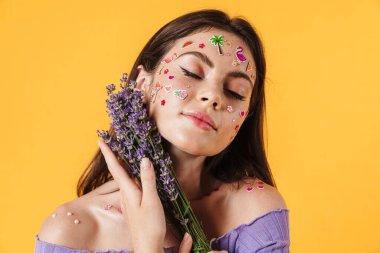 Sarı arkaplanda lavanta çiçekleri tutan yüzü etiketli güzel bir kadın resmi